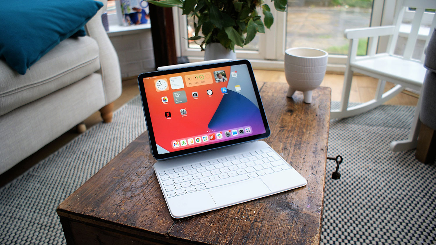 An iPad Air 5 with a Magic Keyboard case sitting on a desk in a brightly lit room.